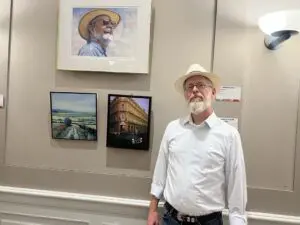 Artist standing in front of wall with paintings on it